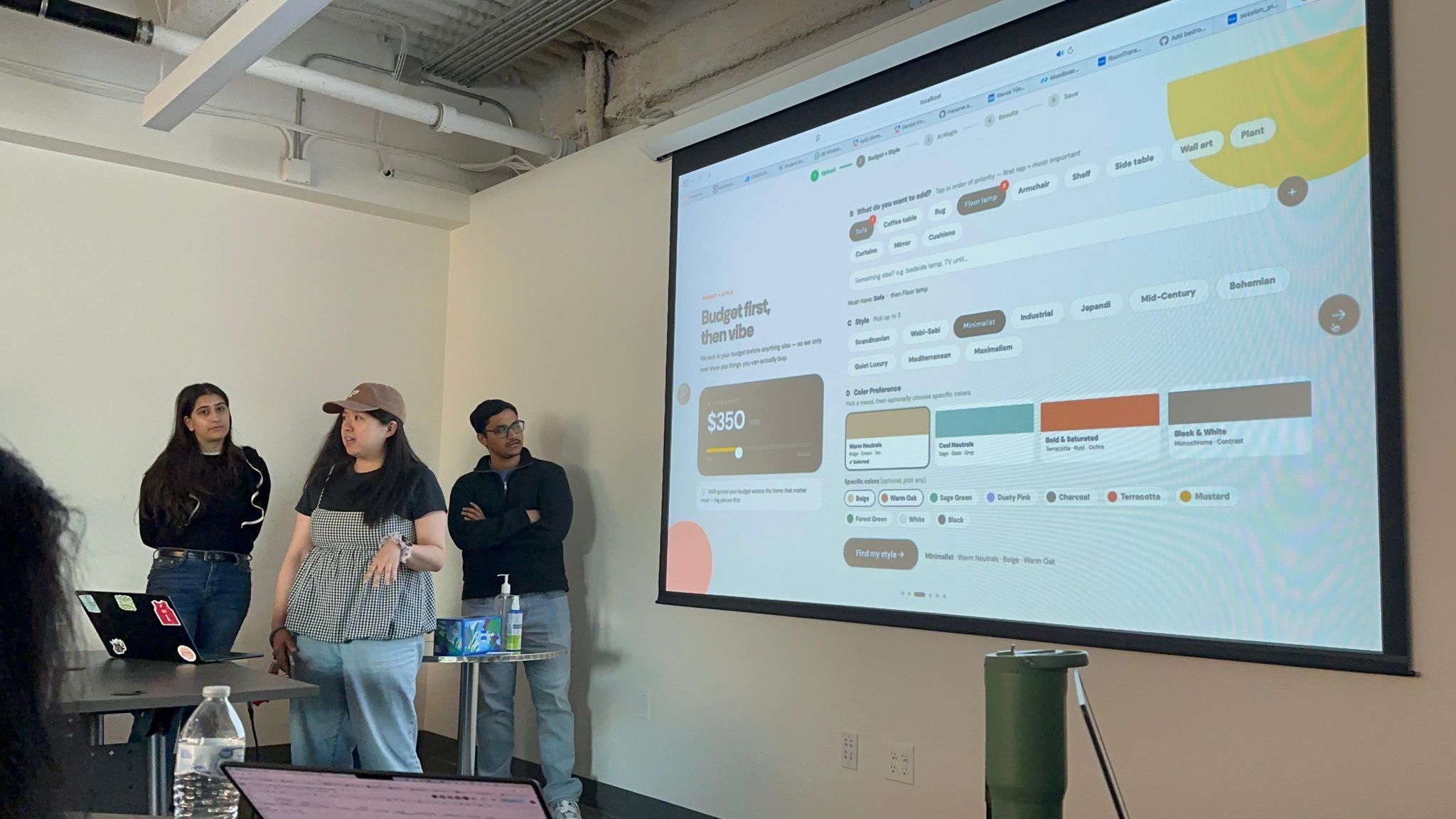 The team demoing on stage, the Budget + Style screen projected behind them
